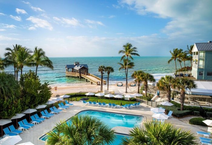 The Reach Key West, Curio Collection by Hilton, a gay-friendly hotel. Pool, beach, pier, and palm trees create a tropical paradise.