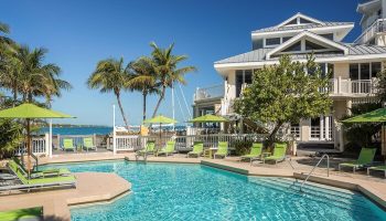 Hyatt Centric Key West Resort pool. Gay-friendly hotel with palm trees, lounge chairs, umbrellas, and ocean views. Perfect for gay men travel.