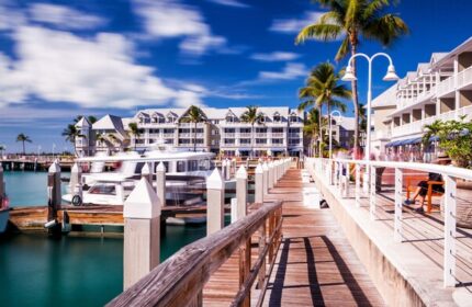 Opal Key Resort and Marina's waterfront view. A gay-friendly hotel, marina, and boardwalk with palm trees, boats, and blue skies. Key West travel.