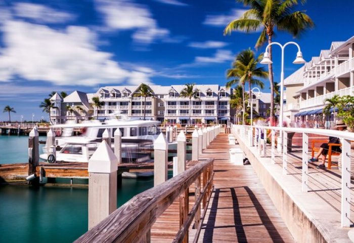 Opal Key Resort and Marina's waterfront view. A gay-friendly hotel, marina, and boardwalk with palm trees, boats, and blue skies. Key West travel.
