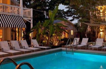 Alexander's Guesthouse pool at night. Gay-friendly hotel with lounge chairs, tropical plants, and ambient lighting. Key West guesthouse.