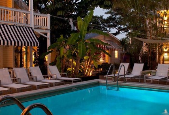 Alexander's Guesthouse pool at night. Gay-friendly hotel with lounge chairs, tropical plants, and ambient lighting. Key West guesthouse.