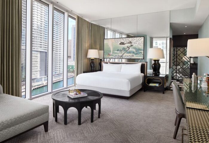 W Miami: Interior of a gay-friendly hotel room. View of the bed, nightstands, and a table. Large windows overlook the city. Modern design.