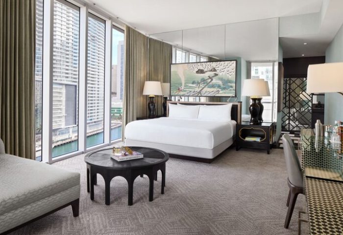 W Miami: Interior of a gay-friendly hotel room. View of the bed, nightstands, and a table. Large windows overlook the city. Modern design.