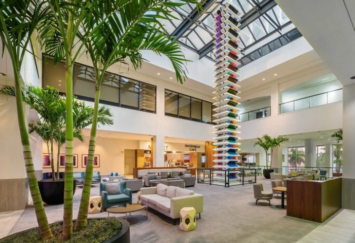 Hyatt Regency Miami lobby. Gay-friendly hotel with palm trees, modern decor, and a tall, colorful sculpture. Riverwalk Cafe. Great for gay travel.