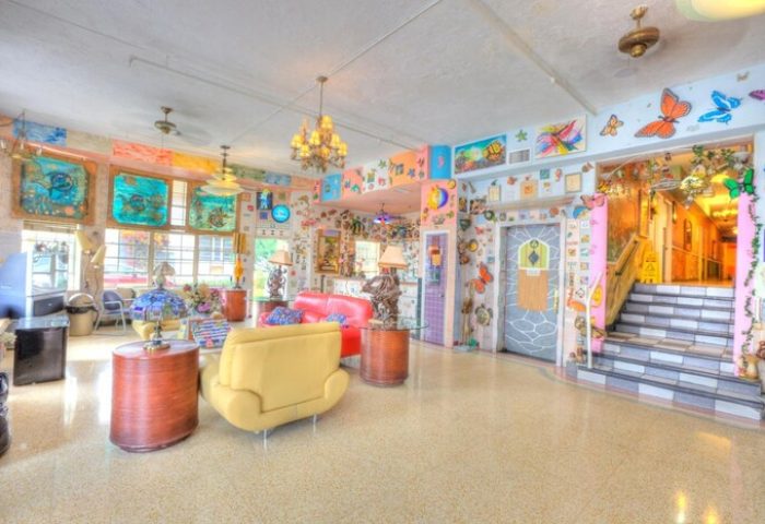 The James Hotel lobby, a gay-friendly hotel. Colorful, with butterflies, paintings, and unique decor. Two sofas, stairs, and an elevator.