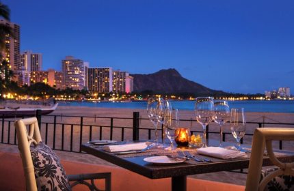 Romantic dinner at The Royal Hawaiian, a Luxury Collection Resort, Waikiki. Gay-friendly hotel with ocean view at dusk. Diamond Head in background.