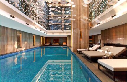 Raffles Istanbul Hotel's indoor pool, a gay-friendly hotel. Elegant design, lounge chairs, and a stunning ceiling installation. Luxury travel.