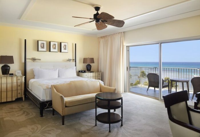 Kahala Hotel & Resort gay-friendly room. Ocean view from balcony. King bed, sofa, ceiling fan. Upscale, luxury travel for gay men.