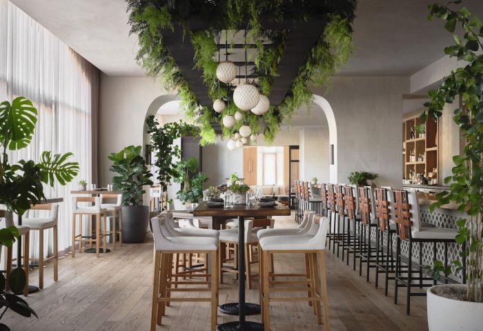 Interior of 1 Hotel San Francisco, a gay-friendly hotel. Bar and high tables with plants. Sustainable design for gay travelers.
