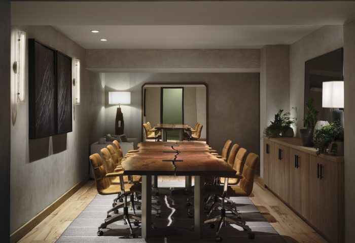 1 Hotel San Francisco's gay-friendly meeting room. Long wooden table with tan chairs. Modern design, plants, and soft lighting.