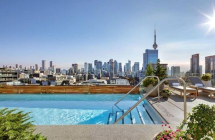 Rooftop pool at 1 Hotel Toronto, a gay-friendly hotel. Toronto skyline view with CN Tower. Loungers offer a relaxing experience.