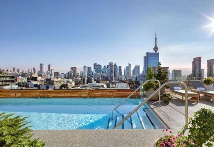 Rooftop pool at 1 Hotel Toronto, a gay-friendly hotel. Toronto skyline view with CN Tower. Loungers offer a relaxing experience.