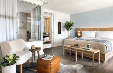1 Hotel Toronto suite. Gay-friendly hotel room featuring a king bed, ensuite bathroom, chair, and ottoman. Modern, clean design.