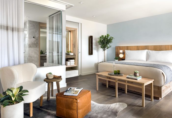 1 Hotel Toronto suite. Gay-friendly hotel room featuring a king bed, ensuite bathroom, chair, and ottoman. Modern, clean design.