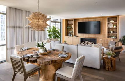 1 Hotel Toronto's gay-friendly design. A living space features a rustic wood table, modern lighting, & a cozy fireplace. Luxury travel.