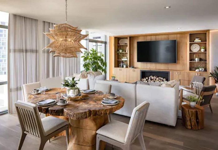 1 Hotel Toronto's gay-friendly design. A living space features a rustic wood table, modern lighting, & a cozy fireplace. Luxury travel.