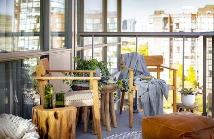 Balcony seating at 1 Hotel Toronto, a gay-friendly hotel. Wood chairs, tree stump tables, and city views create a relaxing, natural vibe.
