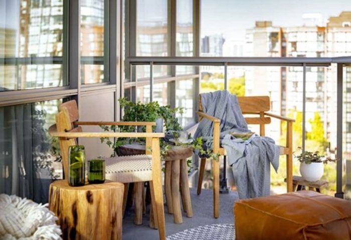 Balcony seating at 1 Hotel Toronto, a gay-friendly hotel. Wood chairs, tree stump tables, and city views create a relaxing, natural vibe.