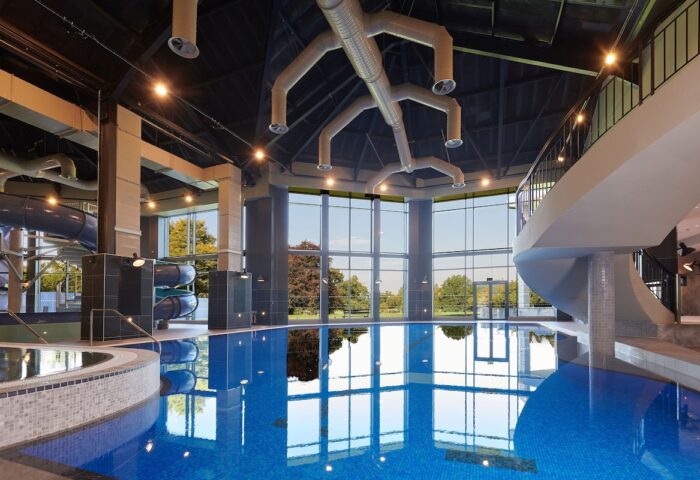 Cameron House on Loch Lomond gay-friendly hotel pool. Blue tiled pool with water slide and floor-to-ceiling windows overlooking greenery.