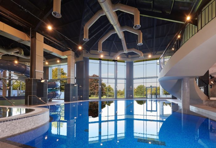 Cameron House on Loch Lomond gay-friendly hotel pool. Blue tiled pool with water slide and floor-to-ceiling windows overlooking greenery.