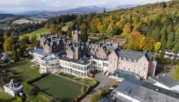 Aerial view of Crieff Hydro, a gay-friendly hotel in Scotland. Resort with mountains, trees, & green lawns. Ideal for gay travel.