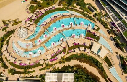 Aerial view of W Dubai - The Palm, a gay-friendly hotel. Pools, beach chairs, and architecture create a luxurious resort experience.