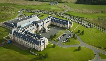 Fairmont St Andrews, Scotland: Aerial view of a gay-friendly hotel. The large, elegant building is surrounded by green lawns and parking areas.