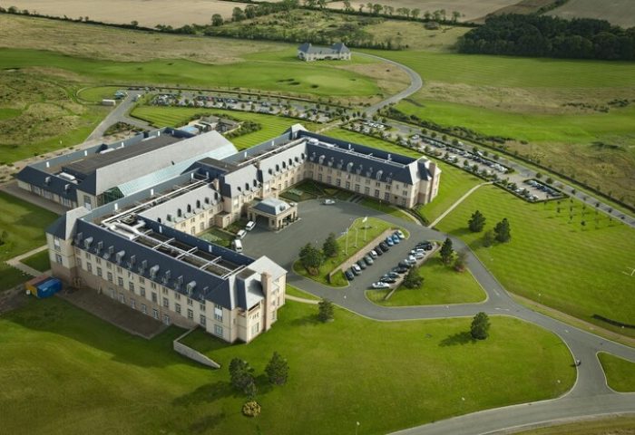 Fairmont St Andrews, Scotland: Aerial view of a gay-friendly hotel. The large, elegant building is surrounded by green lawns and parking areas.