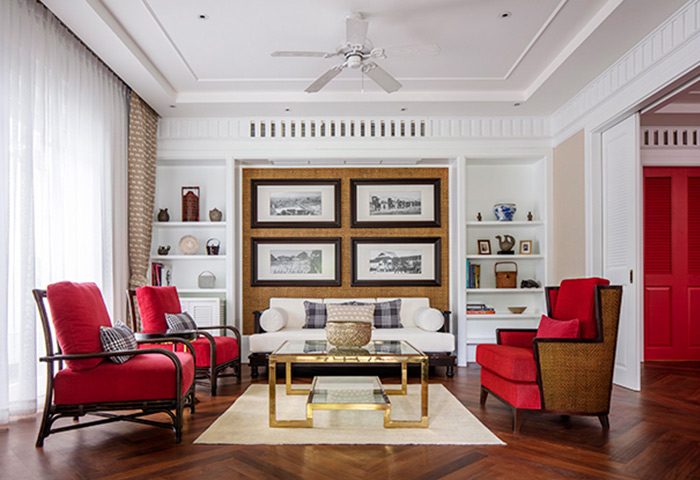 Lounge at 137 Pillars House Chiang Mai, a gay-friendly hotel. Red chairs, white sofa, and art create a stylish, relaxing space.