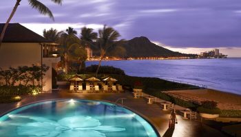 Halekulani Hotel pool at dusk. Gay-friendly hotel with Diamond Head view. Luxury travel for gay men in Hawaii. Oceanfront resort.