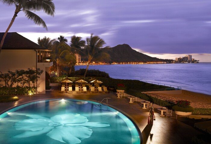 Halekulani Hotel pool at dusk. Gay-friendly hotel with Diamond Head view. Luxury travel for gay men in Hawaii. Oceanfront resort.