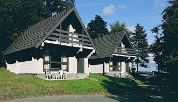 Crieff Hydro, a gay-friendly hotel. Two chalets with A-frame roofs, set on a grassy hill. A great option for gay men's travel.