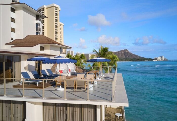 Outrigger Reef Waikiki Beach Resort view. Gay-friendly hotel with oceanfront deck, lounge chairs, umbrellas, and Diamond Head view. Hawaii travel.
