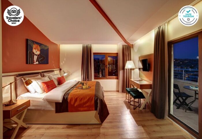 The Fox Hotel room with balcony. Gay-friendly hotel with orange accents, a fox art piece, and city views. Safe Tourism certified.