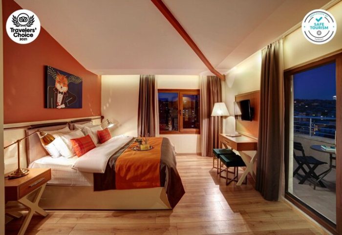 The Fox Hotel room with balcony. Gay-friendly hotel with orange accents, a fox art piece, and city views. Safe Tourism certified.