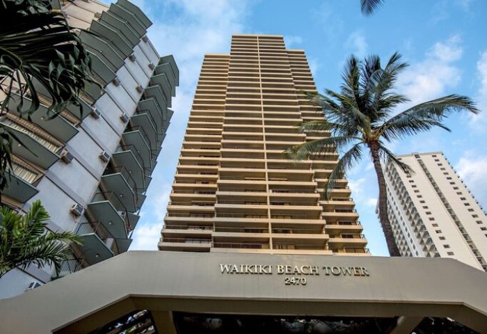 Aston Waikiki Beach Tower, a gay-friendly hotel. High-rise building with balconies and palm trees. A great spot for gay men's travel.