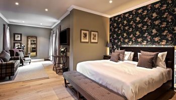 Schloss Roxburghe Hotel gay-friendly room. The suite features a floral accent wall, seating area, king bed, and modern decor. Perfect for gay travel.