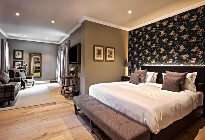 Schloss Roxburghe Hotel gay-friendly room. The suite features a floral accent wall, seating area, king bed, and modern decor. Perfect for gay travel.