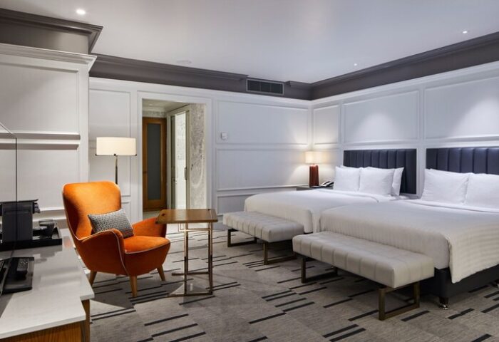 London Marriott Hotel County Hall gay-friendly room. Two beds, orange chair, and stylish decor for gay men's travel. Upscale hotel.