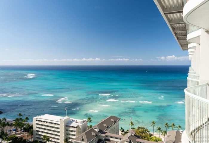 View from Sheraton Princess Kaiulani, a gay-friendly hotel. Turquoise ocean, palm trees, and buildings visible from the balcony.