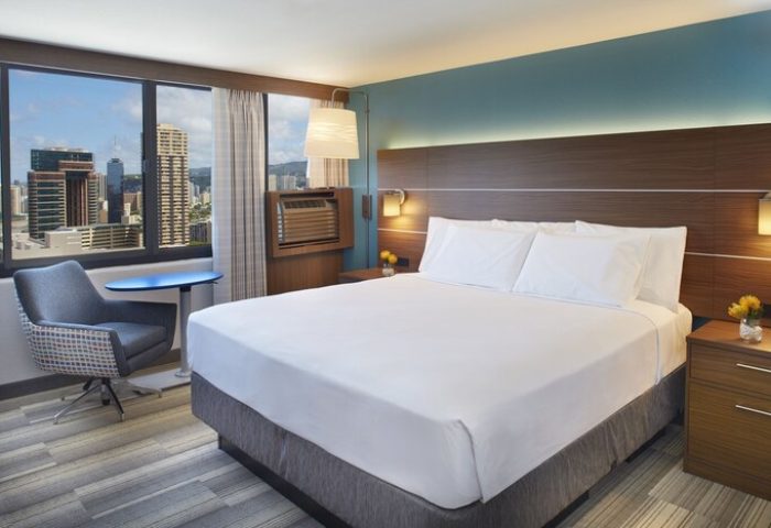 Holiday Inn Express Waikiki gay-friendly hotel room. King bed, city view, chair, and table. Modern design for LGBT travelers.