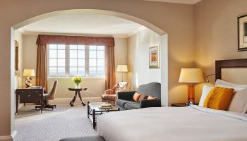 Fairmont St Andrews, Scotland hotel suite. Gay-friendly hotel room with bed, desk, sofa, and window view. Luxury Scottish travel.