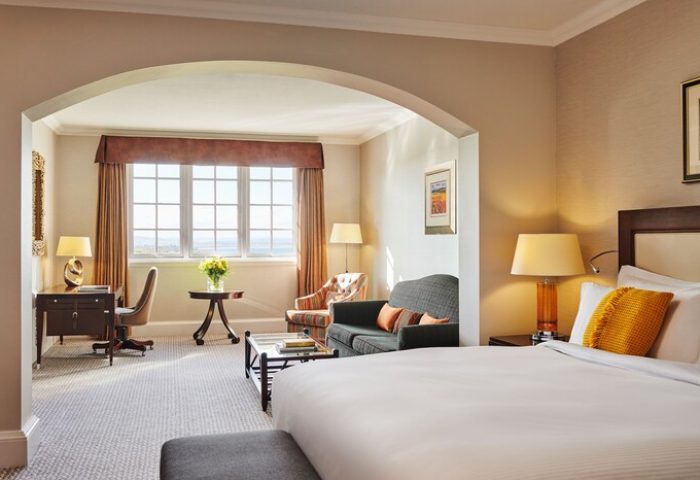 Fairmont St Andrews, Scotland hotel suite. Gay-friendly hotel room with bed, desk, sofa, and window view. Luxury Scottish travel.