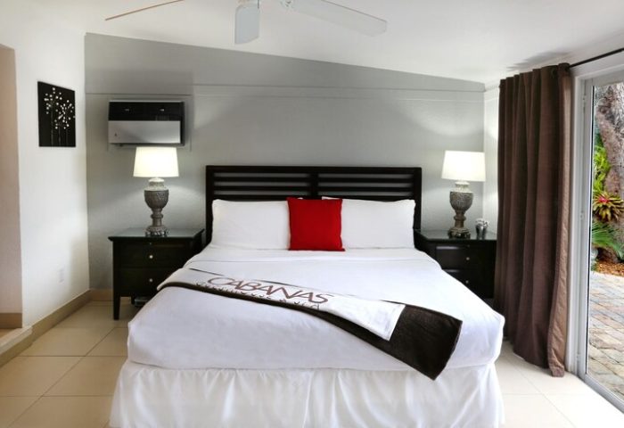 The Cabanas Guesthouse & Spa gay men's resort room. Bedroom with king bed, nightstands, lamps, and patio door. Gay-friendly hotel interior.