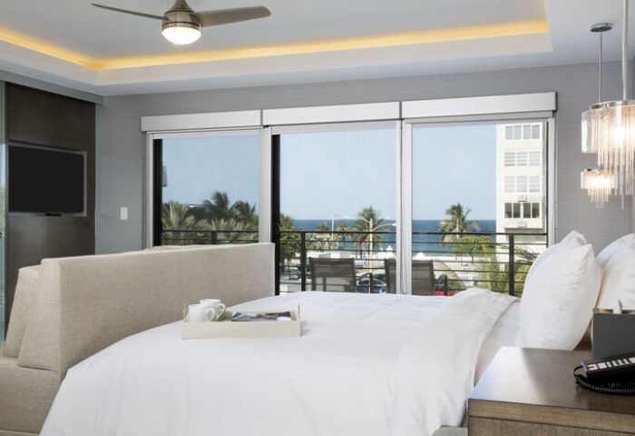Elita Hotel gay-friendly room. Ocean view from balcony. Bed with white linens, tray with coffee. Modern design, for gay men travel.