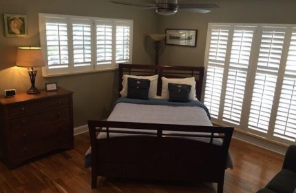 Coral Reef Guesthouse room. Gay-friendly hotel bedroom with a bed, dresser, and shutters. A comfortable space for gay men's travel.