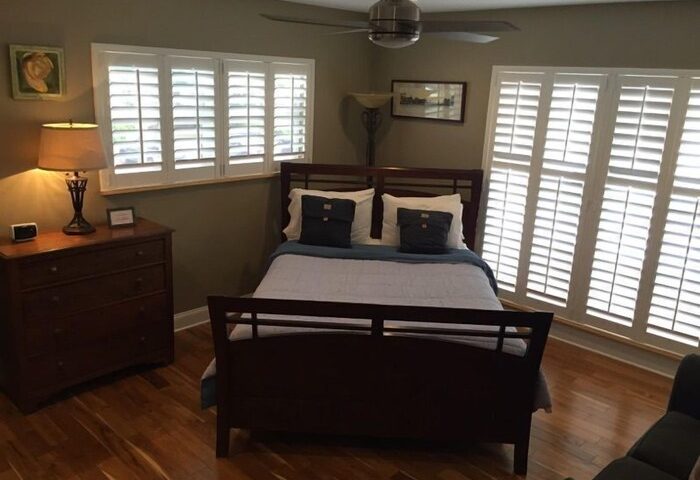 Coral Reef Guesthouse room. Gay-friendly hotel bedroom with a bed, dresser, and shutters. A comfortable space for gay men's travel.