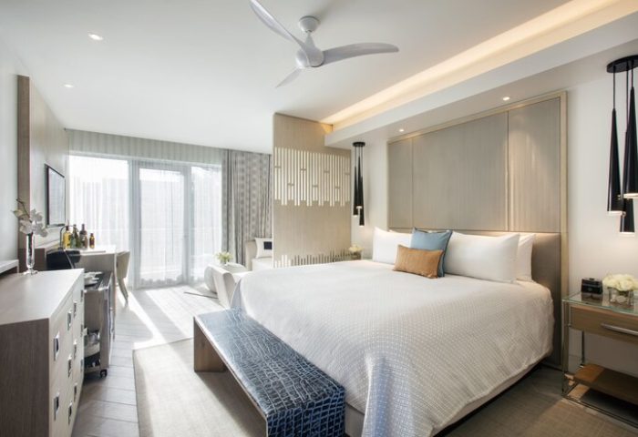 H2O Suites Adults Only gay-friendly hotel room. King-size bed with bench, desk, and balcony. Modern, clean design for gay men's travel.