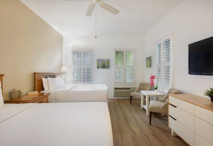 Paradise Inn's gay-friendly hotel room. Adults-only room with two beds, white shutters, TV, and seating area. A comfortable stay.